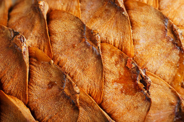 Pine cone peel texture with drops of resin on a gray wooden background. Cedar cone close-up