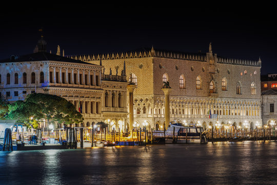 Night view of illuminated Palazzo Ducale (Doges Palace) facade with columns at St. Marks Square, seen from Dorsoduro, Venice, Veneto