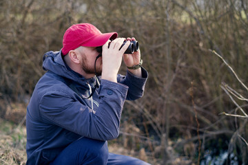 Man with the field-glass watches birds. Ornithology. Birdwatching