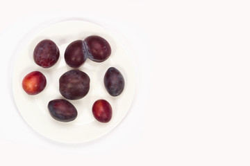 Plums on a plate on a white background.