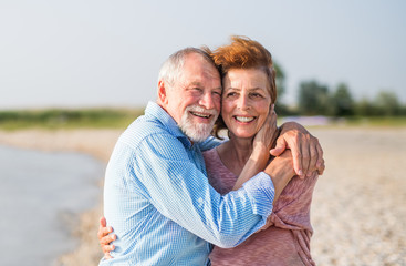 Fototapeta premium Senior couple on a holiday on a walk by the lake, hugging.