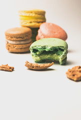 one green macaroon in the foreground lies a bite.Nearby are crumbs from French pastry. In the background,three fresh colored macaroons lie in a pile. Meringue on an isolated background.Selective focus
