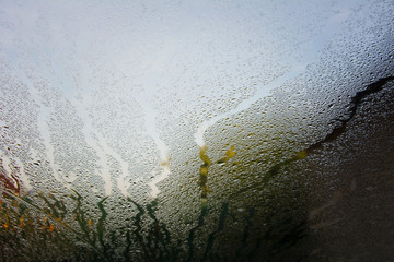 An abstract view of vertical streaks of moisture collected on a steamy glass window.