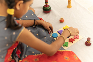 Cute little child girl playing with Indian wooden channapatna toys in the room