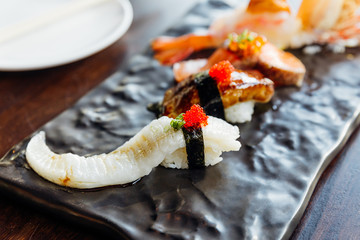 Premium Sushi Set include Deep fried Shrimp with Sea Urchin, Foie Gras, Salmon and Engawa on The Black Stone Plate. Close-up on Engawa Sushi.