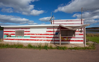 Abandoned, deserted red and white seafood shack.