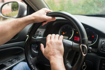 .men's hands on the wheel of a car
