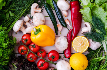 Vegetables and greens on wooden background. Pepper, dill, garlic, lemon, cherry tomatoes.