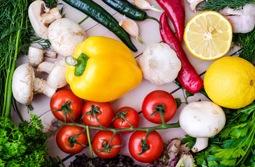 Vegetables and greens on wooden background. Pepper, dill, garlic, lemon, cherry tomatoes.