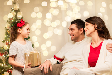 holidays, family and celebration concept - happy mother, father and little daughter with christmas present at home