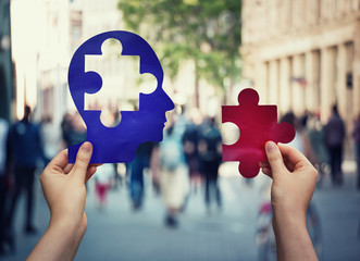 Two hands holding a paper with human head and a puzzle piece. Finding a cure to heal the disease....