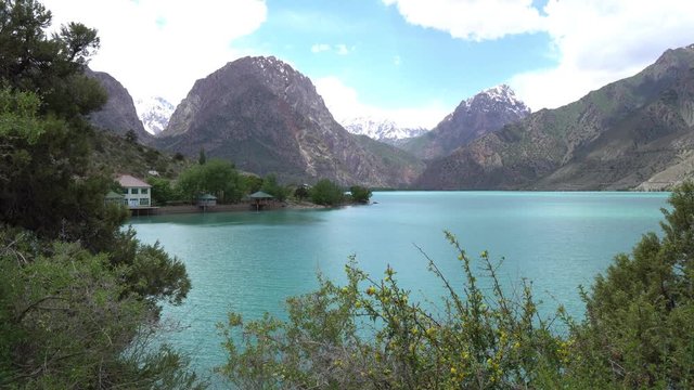 Sughd Iskanderkul Lake Breathtaking Picturesque View with Shore Houses and Snow Capped Mountains at Background on a Sunny Blue Sky Day