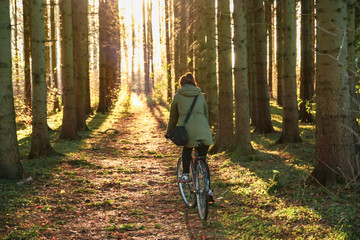 Obraz premium Girl rides a bicycle in the sunny beautiful autumn forest