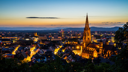 Fototapeta na wymiar Germany, Freiburg im breisgau cityscape and minster or muenster cathedral in magical atmosphere after sunset in summer from famous square above the city