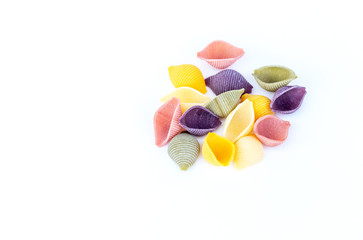 close up of group of conchiglie Italian pasta in the shaped of seashells with yellow, green, pink, and purple colors, isolated on white background.   