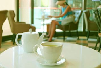 White porcelain tea set of cup and pot on white round table in a cafe