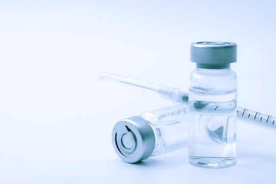 Vaccines, botulinum toxin and insulin ampules concept theme with glass vials with clear liquid next to a syringe and a hypodermic needle isolated on white background