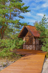 Fototapeta na wymiar A small brick house under a red tiled roof among dunes and pines in a national park (public space). Russia, Kaliningrad, Zelenogradsk, Curonian Spit.
