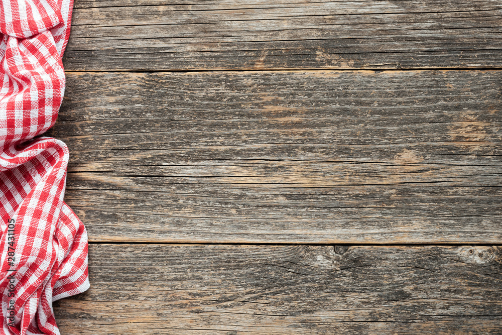 Wall mural Red checkered picnic textile on rustic wooden planks background. Top view copy space. Cooking, food menu background