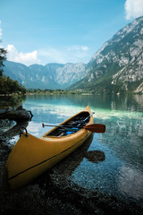 canoeing in the lake bohinj on a summer day, background alps mountains.