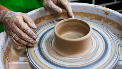 Fototapeta na wymiar A raw clay pot in the hands of a potter. Workshop in the pottery workshop. Clay pot on a potter`s wheel