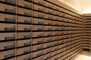 Numbered mailboxes and lockers in raw in the condo. Natural wooden letterbox panel pattern