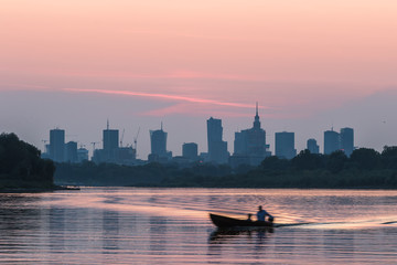 Fototapeta premium Colorful Warsaw cityscape with skyscrapers in the downtowan and a boat sailing on the Vistula River during 