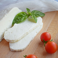 Home-made sliced Adyghe cheese lying on wooden board.