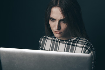Social bullying concept. Sad and empty woman using computer and feeling depressed. Harrasment...