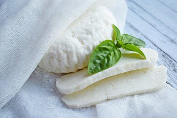 Home-made sliced Adyghe cheese lying on wooden board.