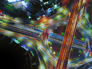 Aerial view of circle road traffic in roundabout and highway at night, Expressway, Modern transportation, Multilevel junction highway, Important infrastructure of transport in Thailand, Top view.