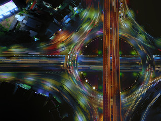 Aerial view of circle road traffic in roundabout and highway at night, Expressway, Modern transportation, Multilevel junction highway, Important infrastructure of transport in Thailand, Top view.