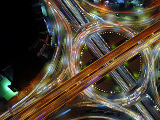 Aerial view of circle road traffic in roundabout and highway at night, Expressway, Modern transportation, Multilevel junction highway, Important infrastructure of transport in Thailand, Top view.