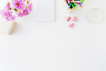 Flat lay blogger or freelancer workspace with a notebook, pink flowers on a white background