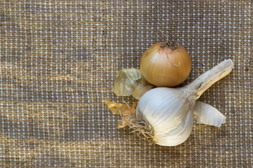 Head of garlic and onion lie on a table on a burlap