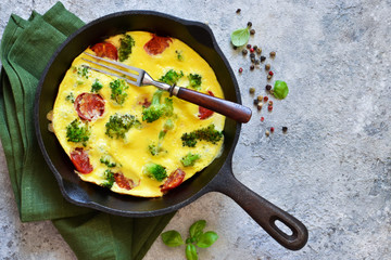 Omelet with vegetables in a cast-iron pan on the table.