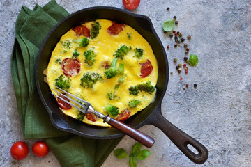 Omelet with vegetables in a cast-iron pan on the table.