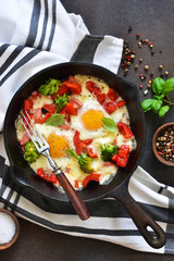 Fried eggs with tomatoes, peppers and broccoli for breakfast on the kitchen table. Good morning.