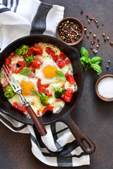 Fried eggs with tomatoes, peppers and broccoli for breakfast on the kitchen table. Good morning.