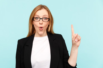 Happy pretty woman in glasses pointing something in the blue studio
