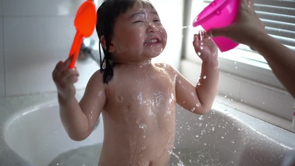 Cute Little child Having a Bath,Wash hair by Mom's hands washing  Asian girl head in the bathroom. The symbol of purity and hygiene education