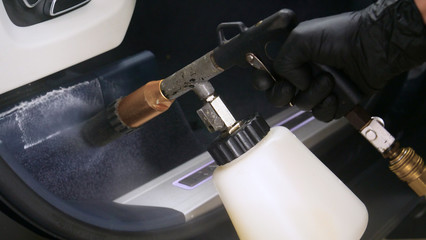 A woman at a car wash does a full dry-cleaning of all parts of a car using special chemistry, cloths, sponges and brushes. Concept of: Full car cleaning, Dry cleaning, Professional service. Car, Work.