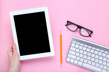 Tablet and computer keyboard with glasses on pink background