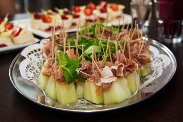 Italian appetizer: melon with ham on a plate close up