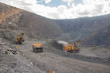 mining machinery works in a quarry. Trucks are transporting ore. excavators load ore into dump trucks.