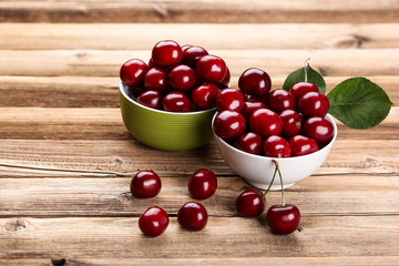 Sweet cherries in bowls on brown wooden table