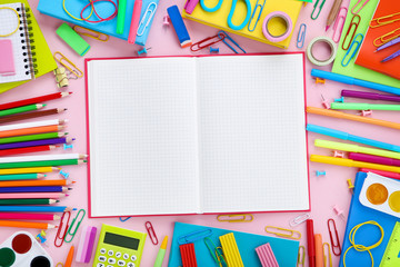 Different school supplies with opened notebook on pink background