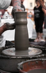 Hands of a potter shaping a clay pot on a potter wheel