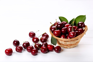 Sweet cherries in basket on white wooden table