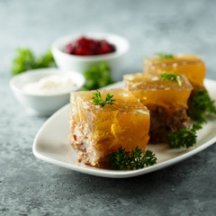 Festive meat jelly with sauces on white plate